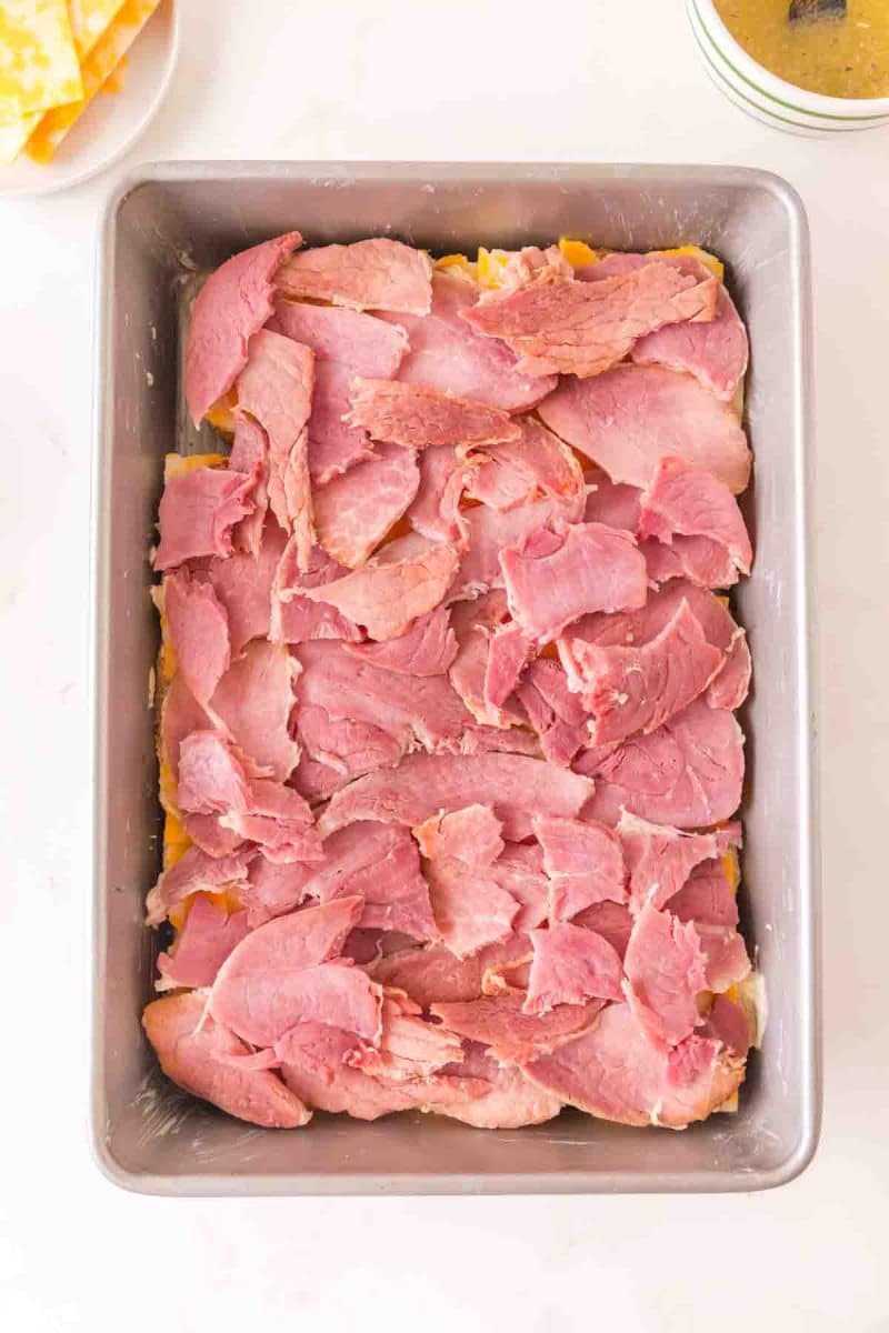 Layering sliced ham evenly over cheese on Hawaiian roll sliders. Hostess At Heart