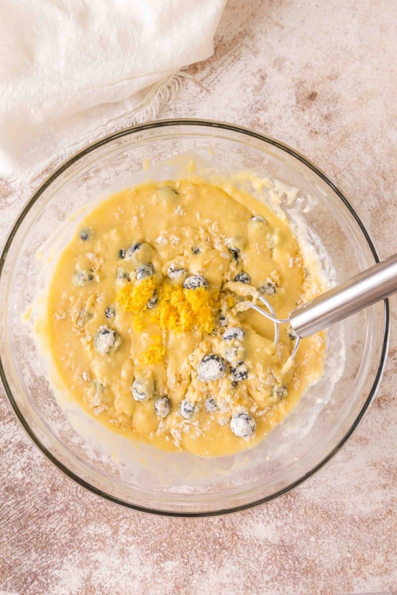Gently folding flour-coated blueberries and lemon zest into sourdough bread batter - Hostess At Heart