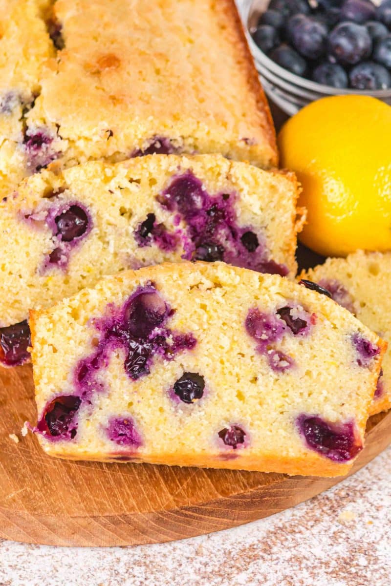 Slices of lemon blueberry sourdough bread showing tender crumb and blueberries on a cutting board - Hostess At Heart