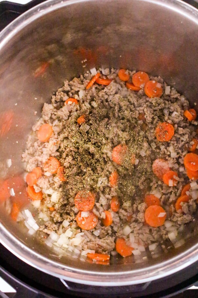 Spices added to browned sausage, carrots, and onions in a pressure cooker. - Hostess At Heart