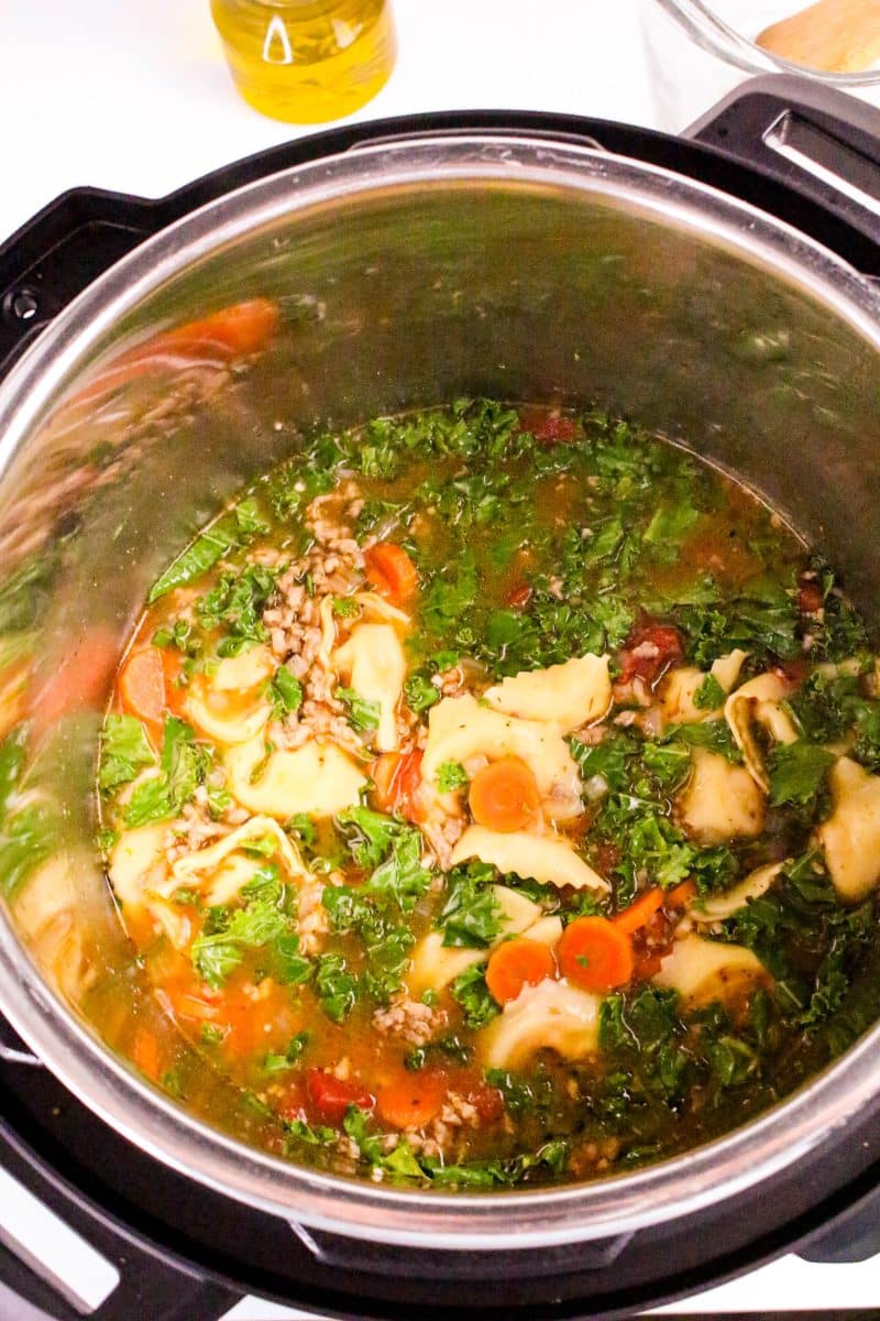 Final stir after adding fresh kale into Italian sausage tortellini soup after pressure cooking - Hostess At Heart