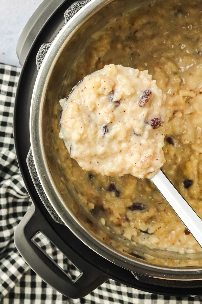 A ladle filled with warm rice pudding hovering over the instant pot. Hostess At Heart