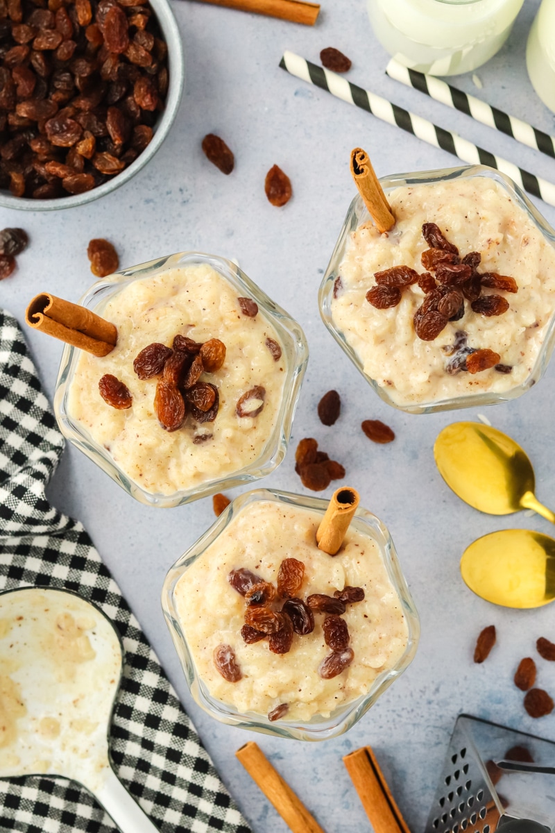 Three dessert cups filled with creamy instant pot rice pudding topped with cinnamon and raisins. Hostess At Heart
