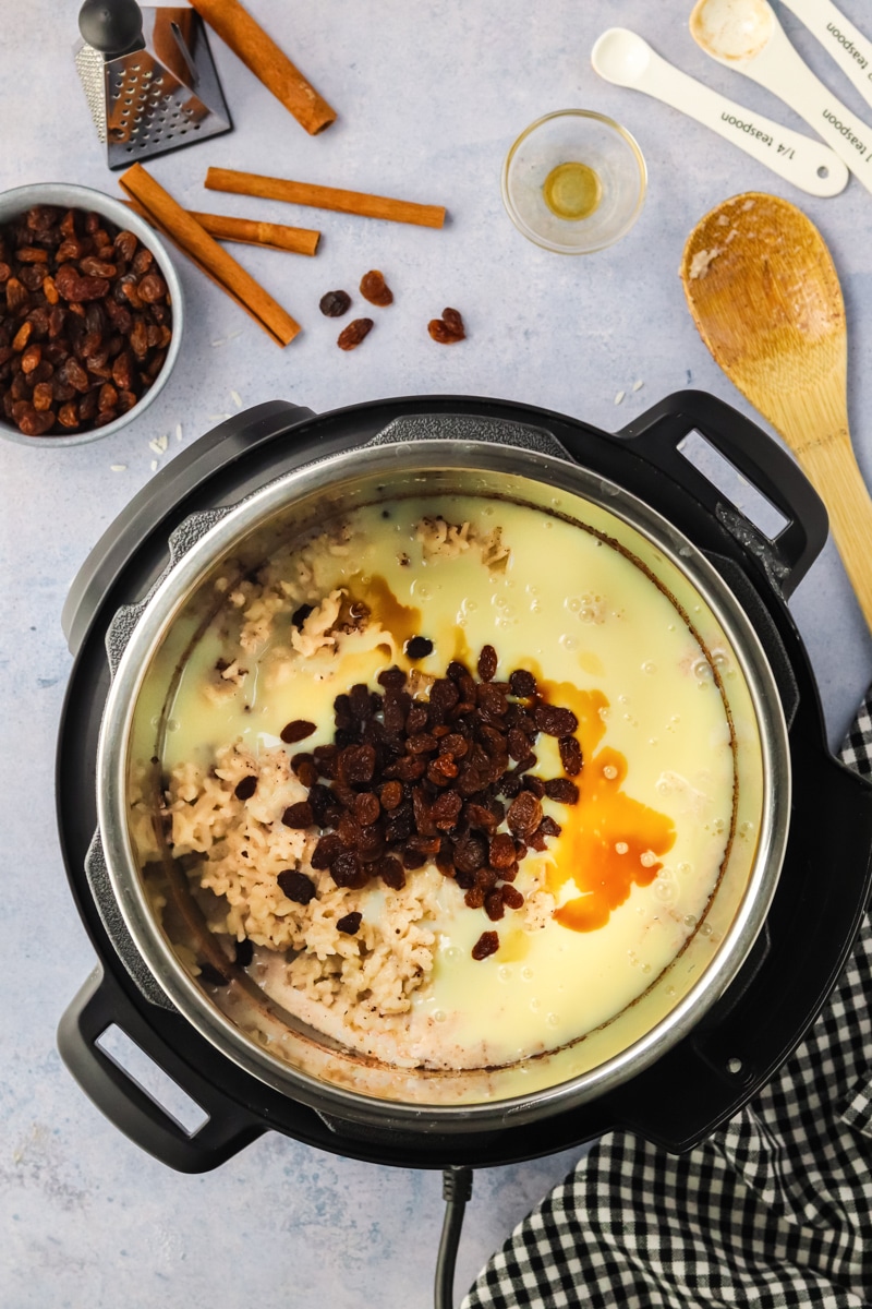 Sweetened condensed milk, vanilla, raisins added to an instant pot filled with cooked rice - Hostess At Heart