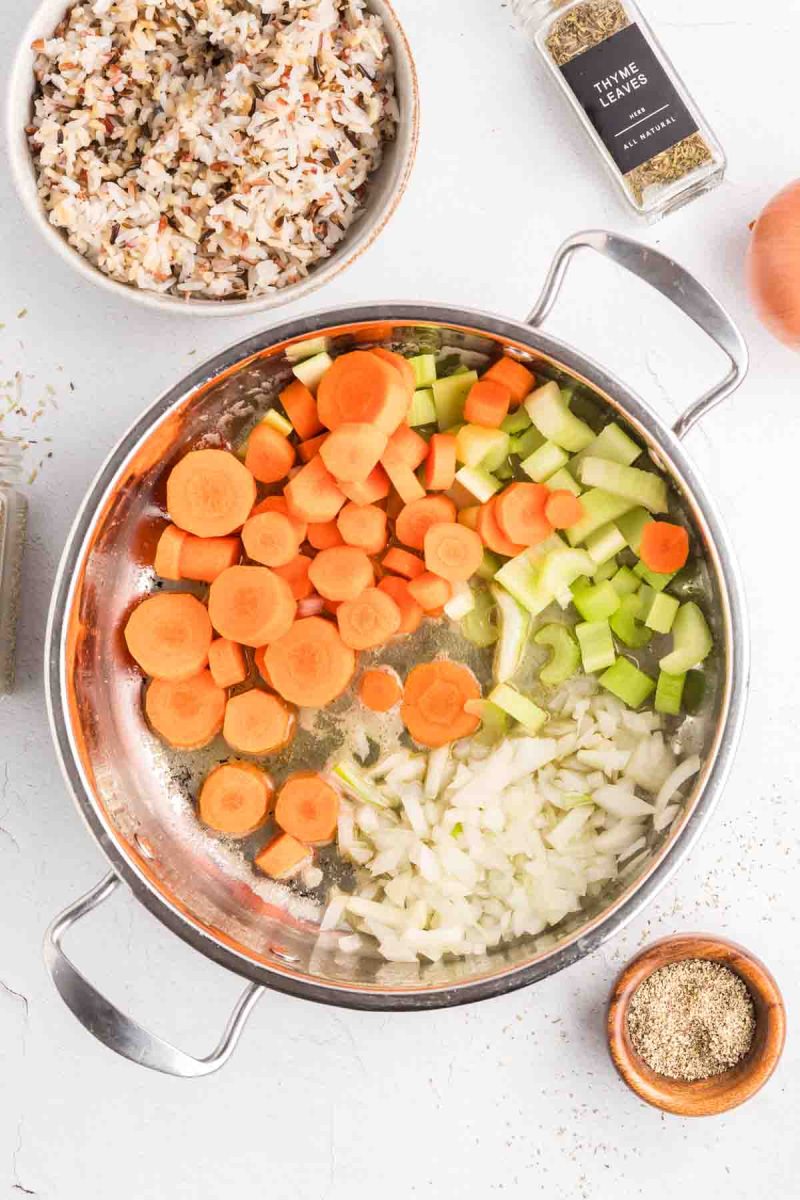 Diced onions, carrots, and celery cooking in butter and oil in a large pot for chicken and wild rice soup. Hostess At Heart