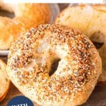 An image for pinterest of a homemade everything bagel propped up against other homemade bagels. Hostess At Heart