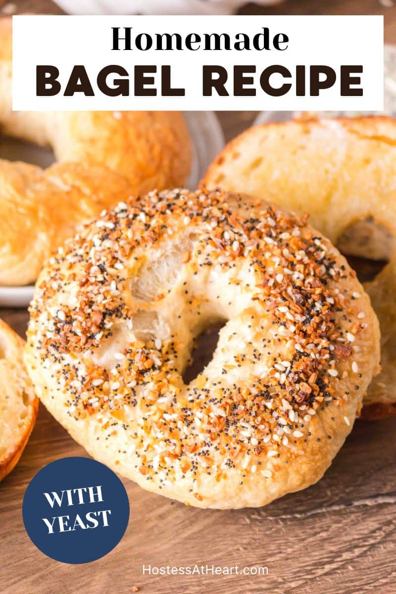 An image for pinterest of a homemade everything bagel propped up against other homemade bagels. Hostess At Heart