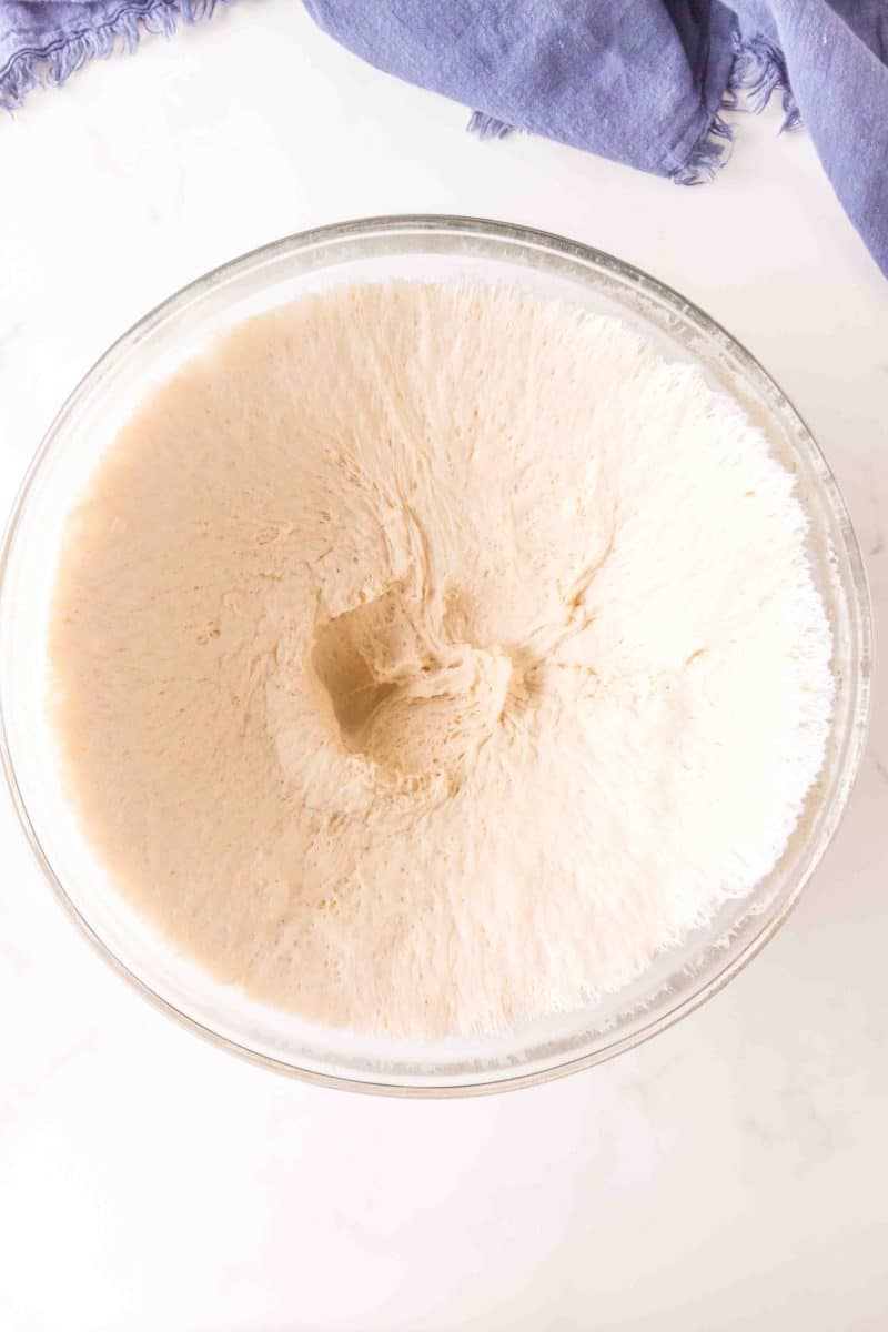 A mixing bowl filled with risen dough that's been punched down to deflate. Hostess At Heart