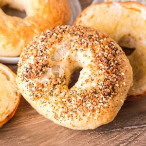 A freshly baked everything bagel propped up against other freshly baked bagels - Hostess At Heart