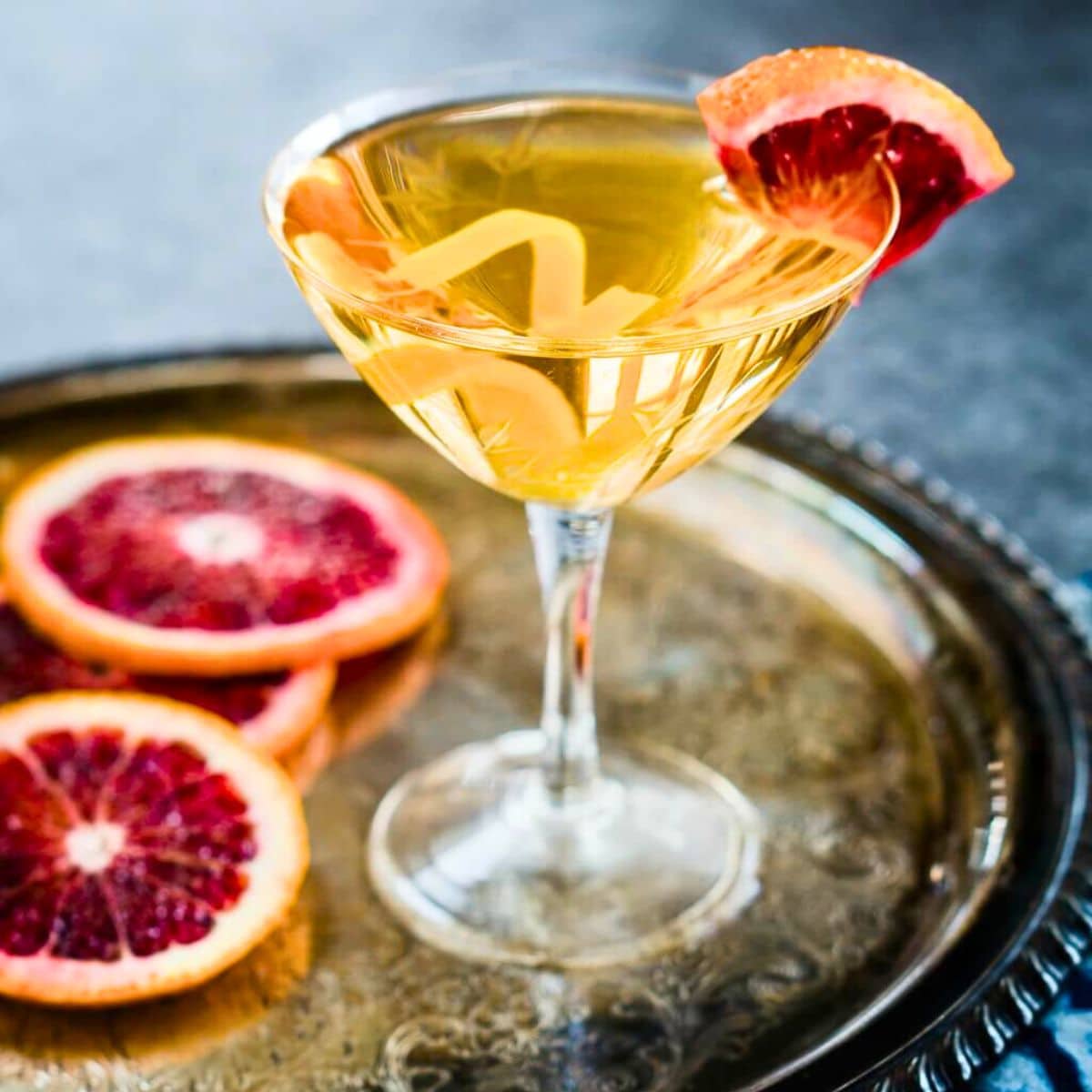 Front view of a Blood Orange Vodka Cocktail garnished with a wedge of blood orange and lemon spiral in a coupe glass