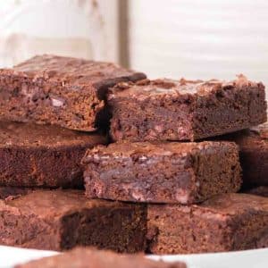 Stack of fudgy sourdough discard brownies with chocolate chips on white plate - Hostess At Heart