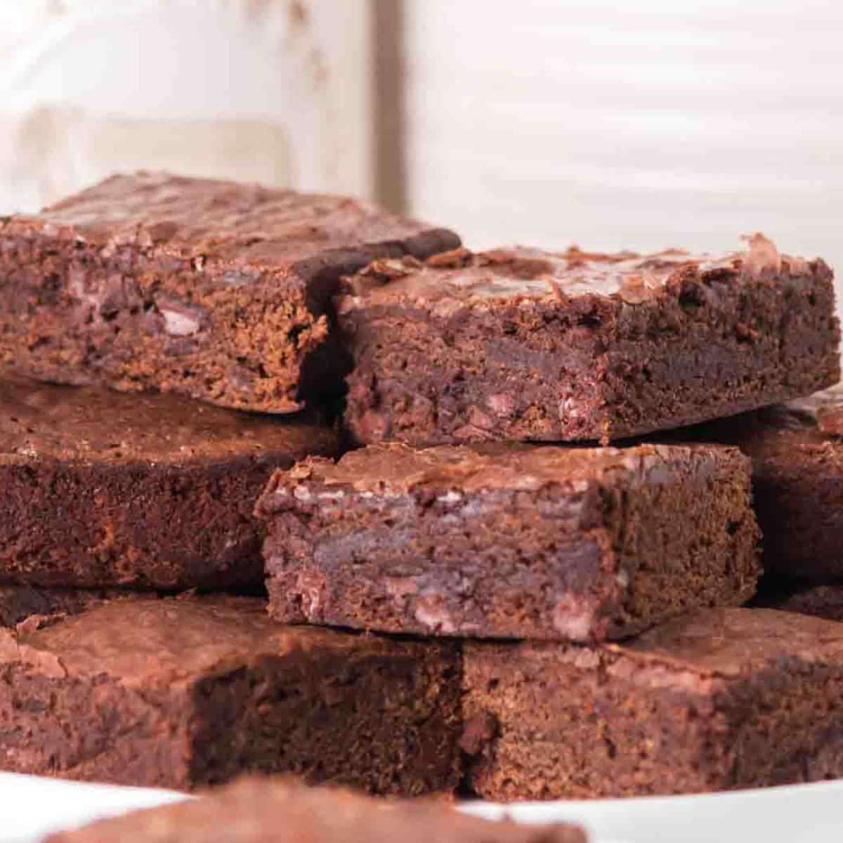 Stack of fudgy sourdough discard brownies with chocolate chips on white plate - Hostess At Heart
