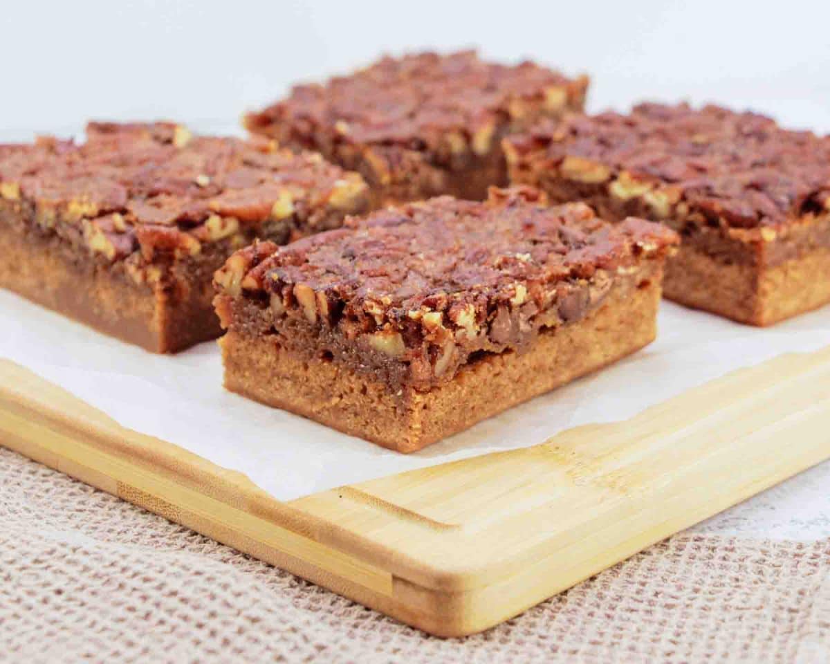 Sideview of Derby pie brownies with chocolate chips and pecans on parchment paper - Kentucky Derby desserts - Hostess At Heart