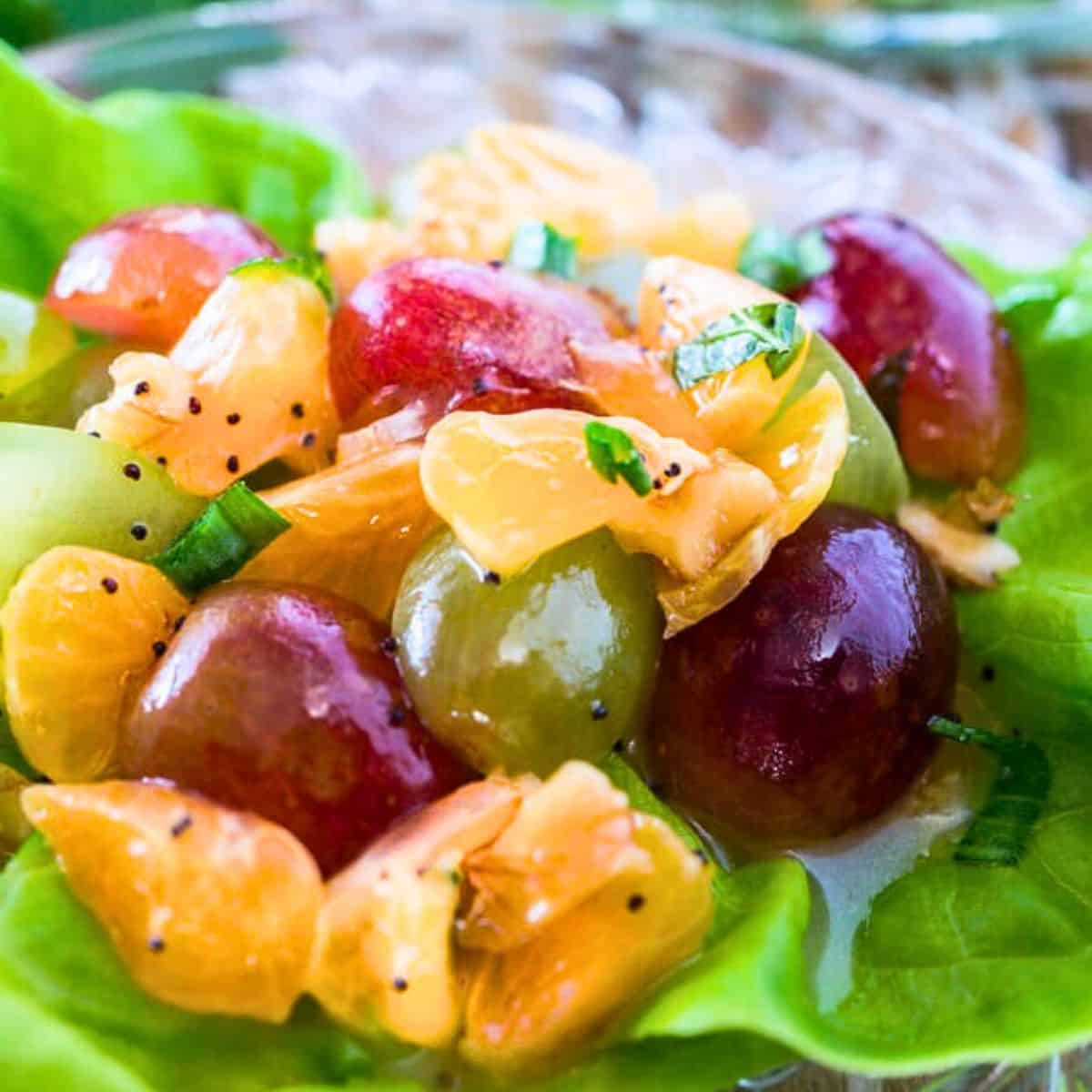 Closeup view of an easy Grape Salad recipe with clementines and a sweet poppyseed sauce on a butter lettuce leaf. Hostess At Heart