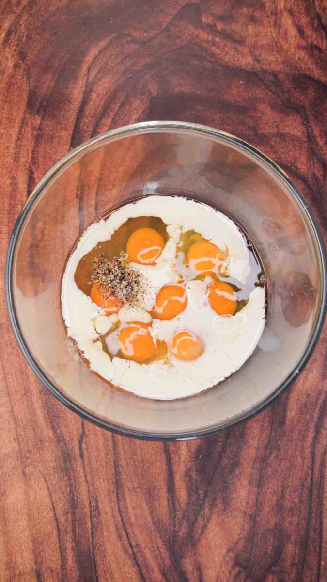7 eggs in a glass bowl filled with milk, salt, and pepper - Hostess At Heart