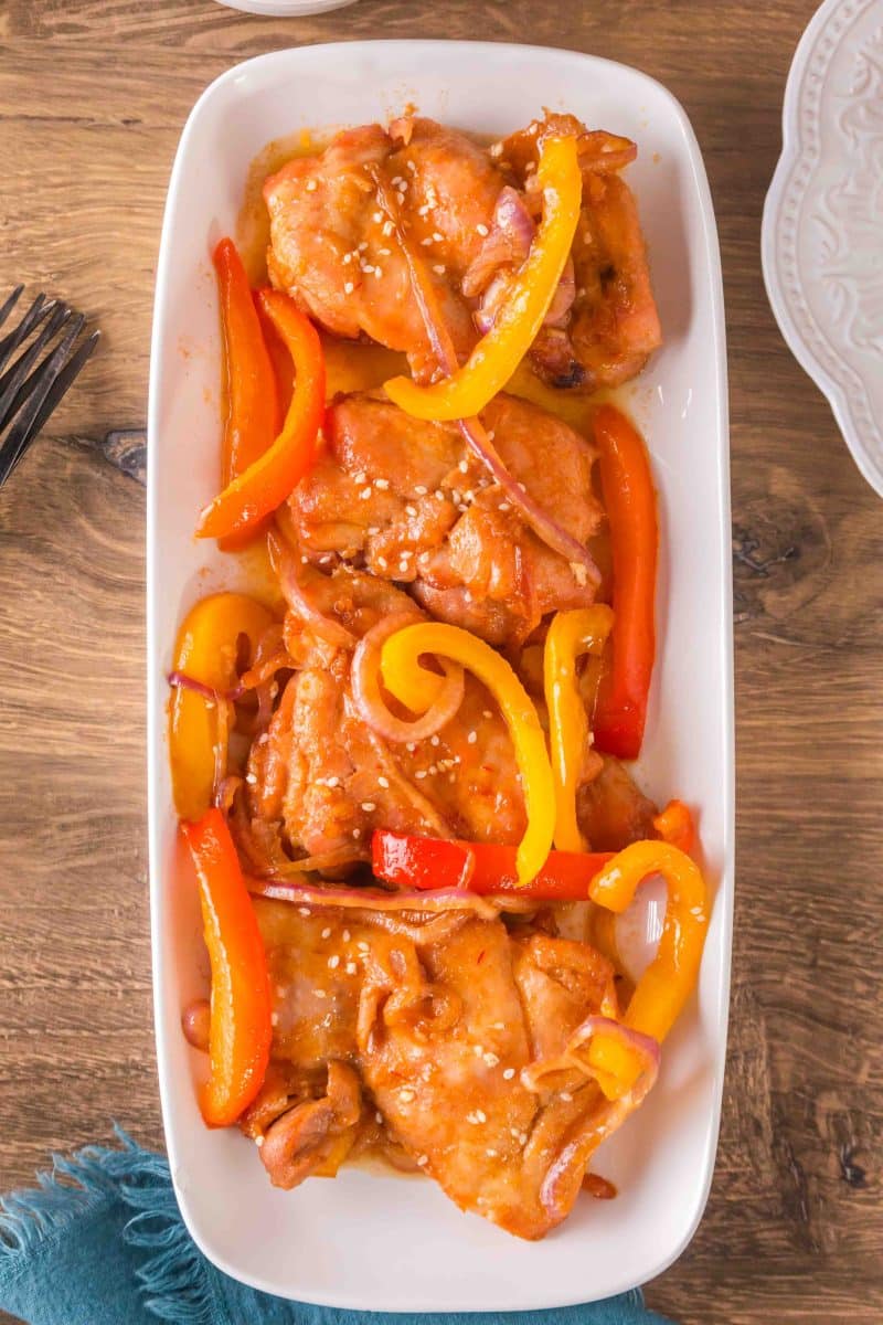 Serving platter filled with garlic honey chicken thighs and vegetables, garnished with sesame seeds - Hostess At Heart