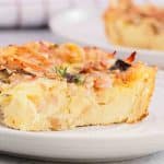 Close up of breakfast strata slice showing custardy bread, melted cheese, ham and mushrooms. Hostess At Heart