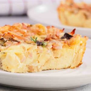 Close up of breakfast strata slice showing custardy bread, melted cheese, ham and mushrooms. Hostess At Heart