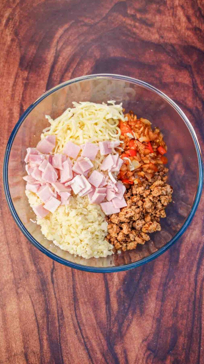 Ingredients for breakfast casserole including sausage eggs and hashbrowns in a glass dish before being combined - Hostess At Heart