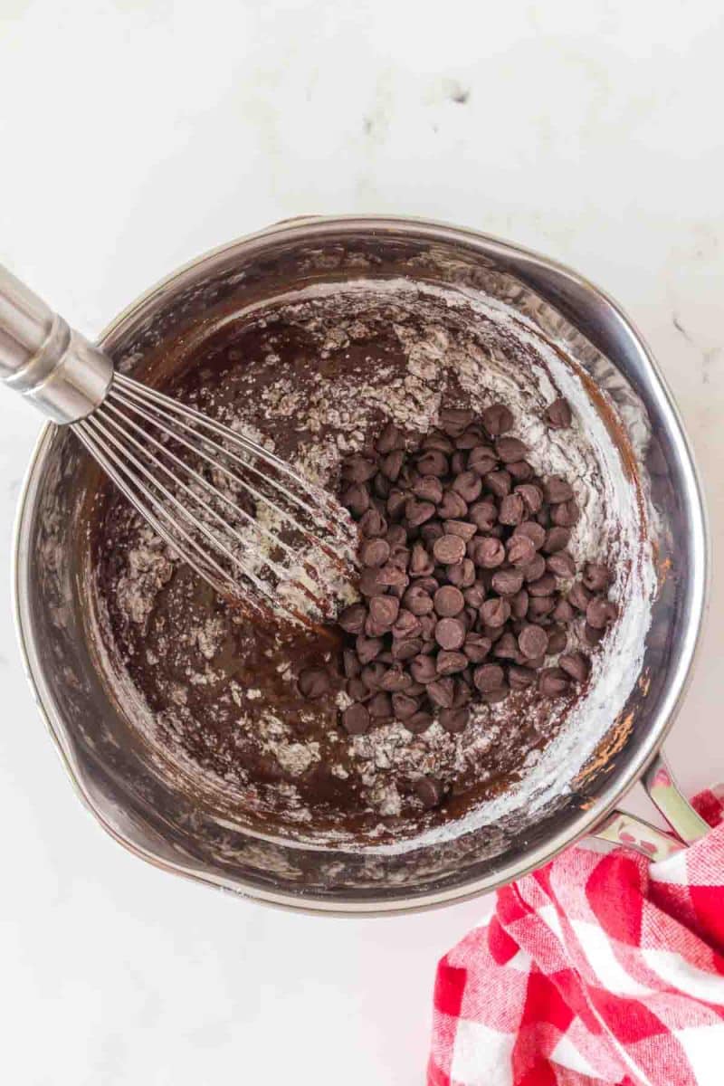 Chocolate chips added to sourdough brownie batter in a mixing bowl - Hostess At Heart