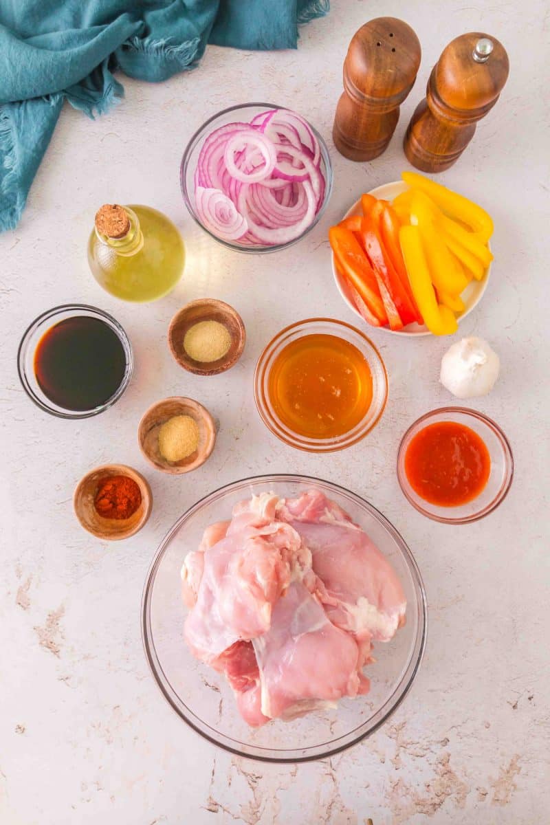 Ingredients to make Sheet Pan Honey Garlic Chicken Thighs: boneless, skinless chicken thighs, soy sauce, paprika, honey, garlic powder, bell peppers, red onion, onion powder, fresh garlic, and olive oil. Hostess At Heart