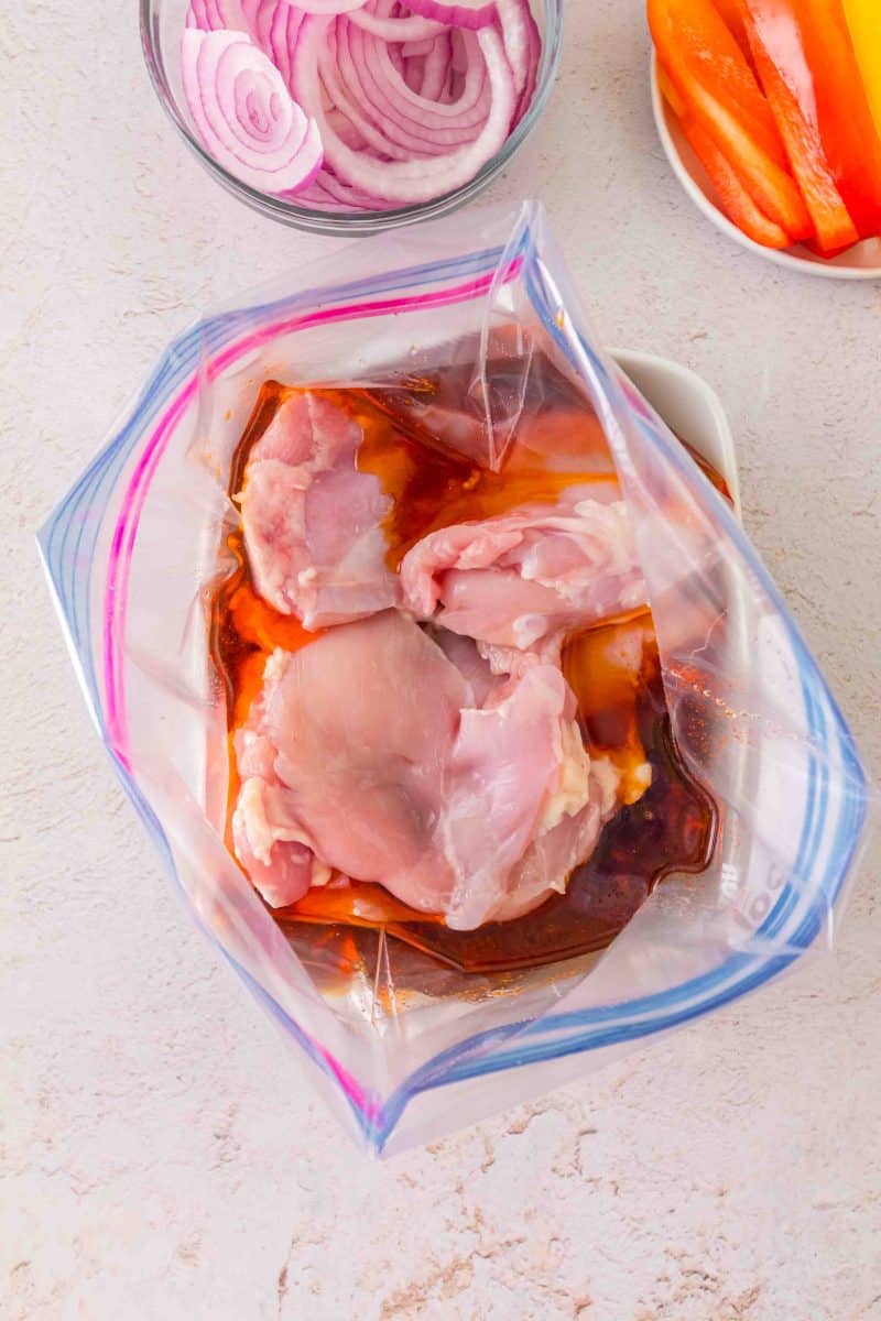 Raw chicken thighs in ziplock bag being coated with honey garlic marinade. Hostess At Heart