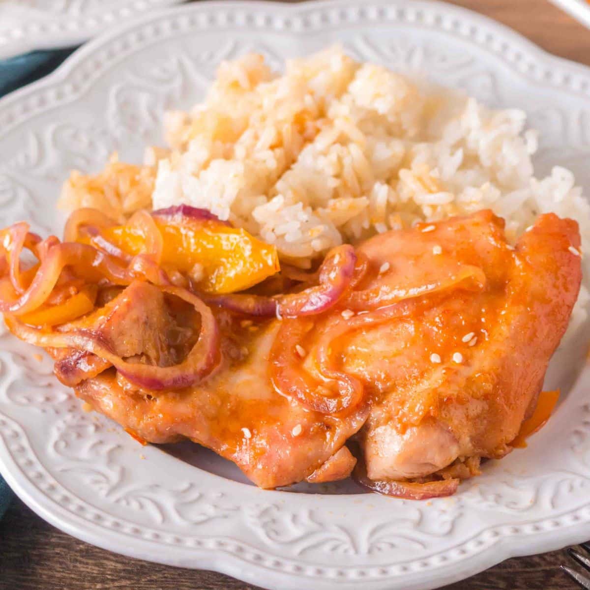 Angled view of plated garlic honey chicken and vegetables next to a serving of white rice. Hostess At Heart