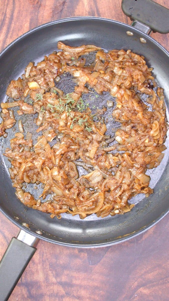 Fresh thyme added to a skillet of perfectly caramelized onions. Hostess At Heart