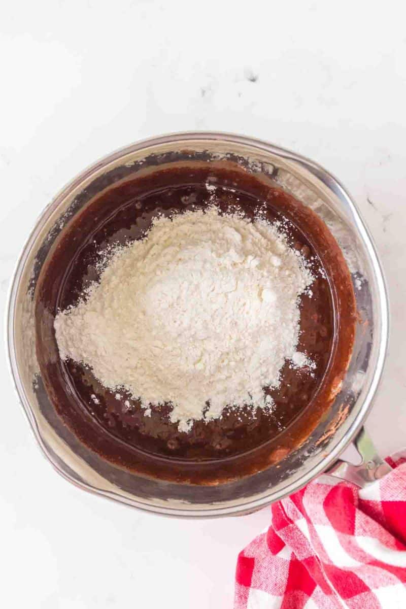 Flour added to a mixing bowl filled with chocolate sourdough brownie batter - Hostess At Heart