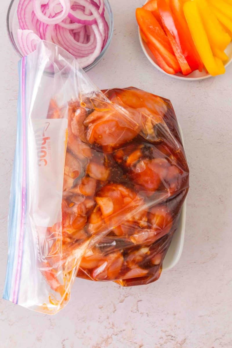 Raw chicken thighs in ziplock bag being coated with honey garlic marinade. Hostess At Heart