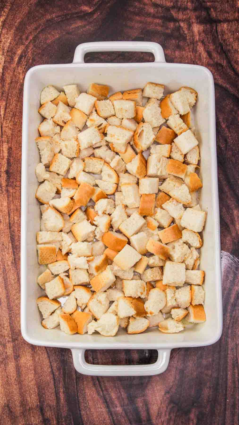 A baking dish with a layer of cubed bread covering the bottom. Hostess At Heart