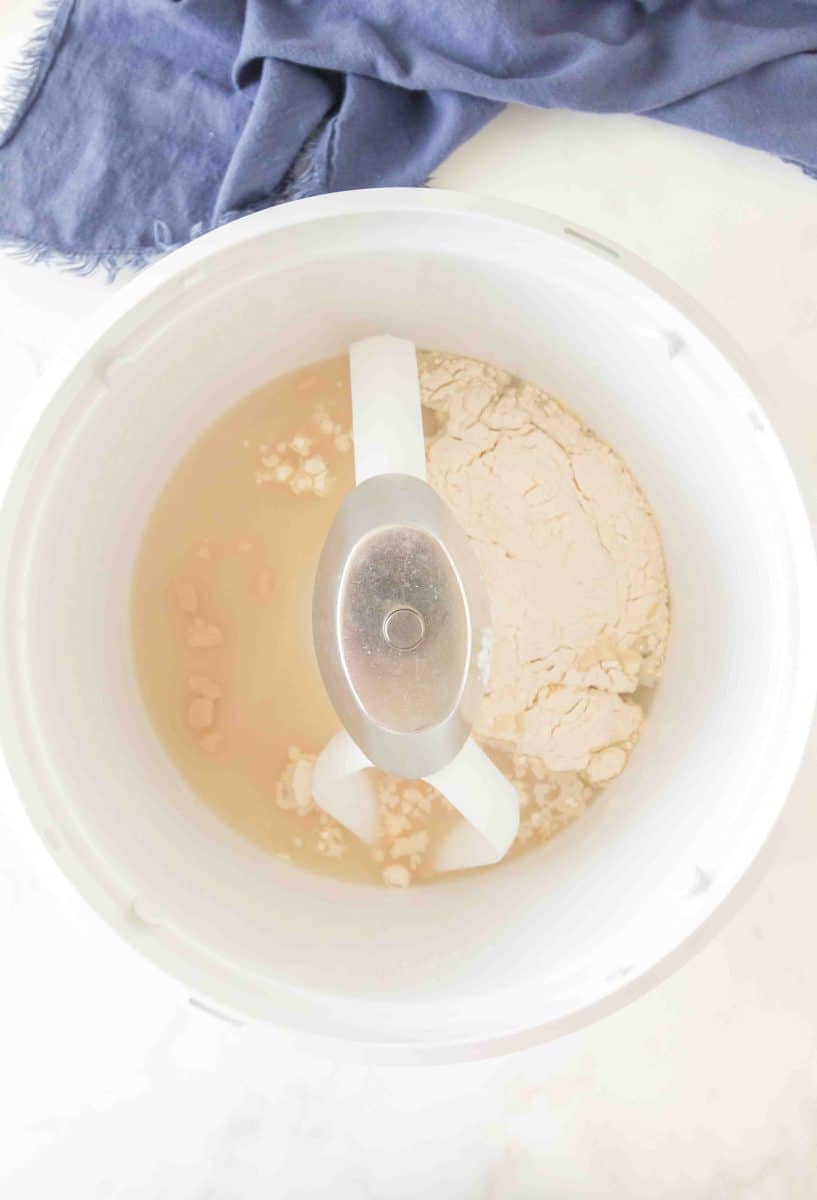 A mixer filled with homemade bagel dough ingredients including flour, salt, water, and yeast. Hostess At Heart