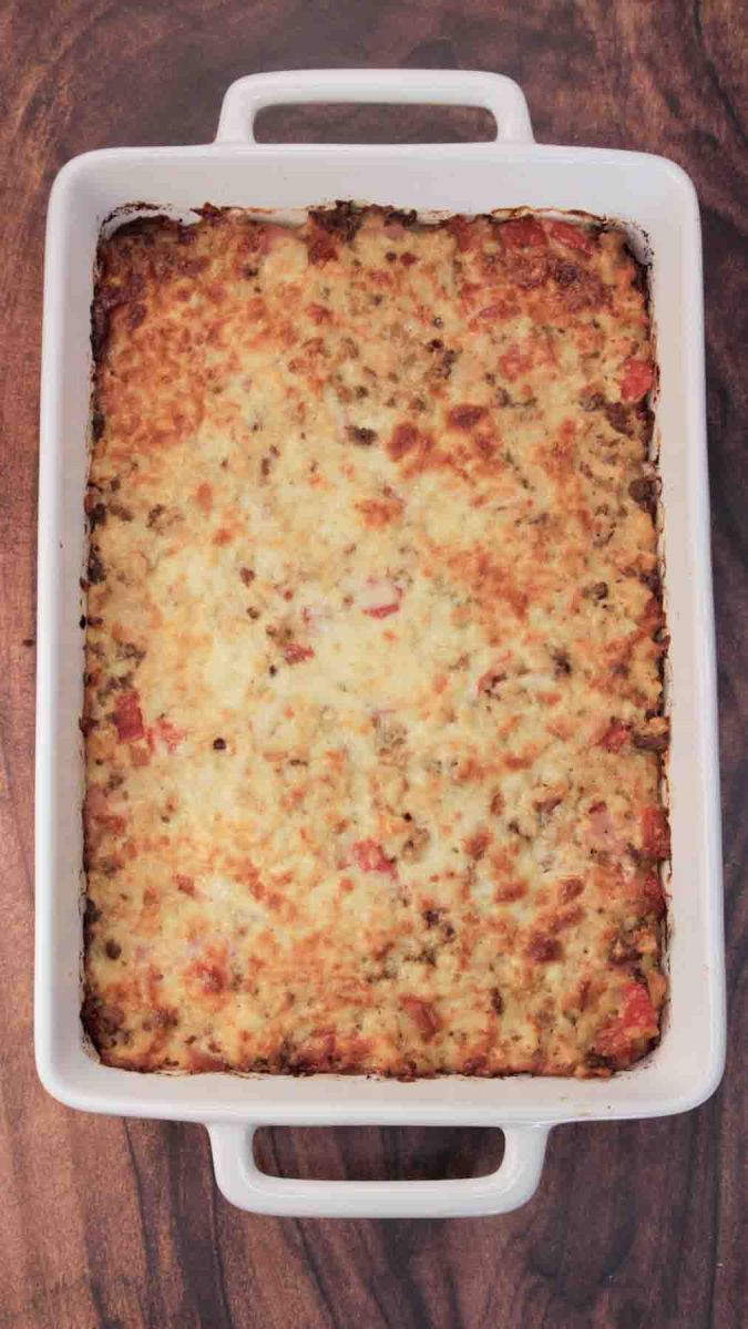 Top down view of a golden brown egg and sausage casserole with melted cheese fresh from oven. Hostess At Heart