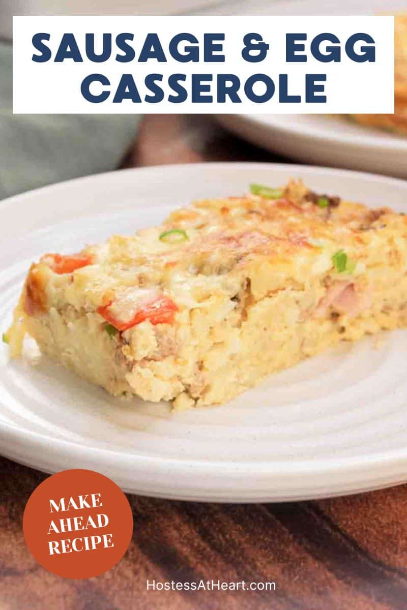 An image for Pinterest of a slice of Golden brown egg, sausage and hashbrown casserole with melted cheese on a white plate. Hostess At Heart