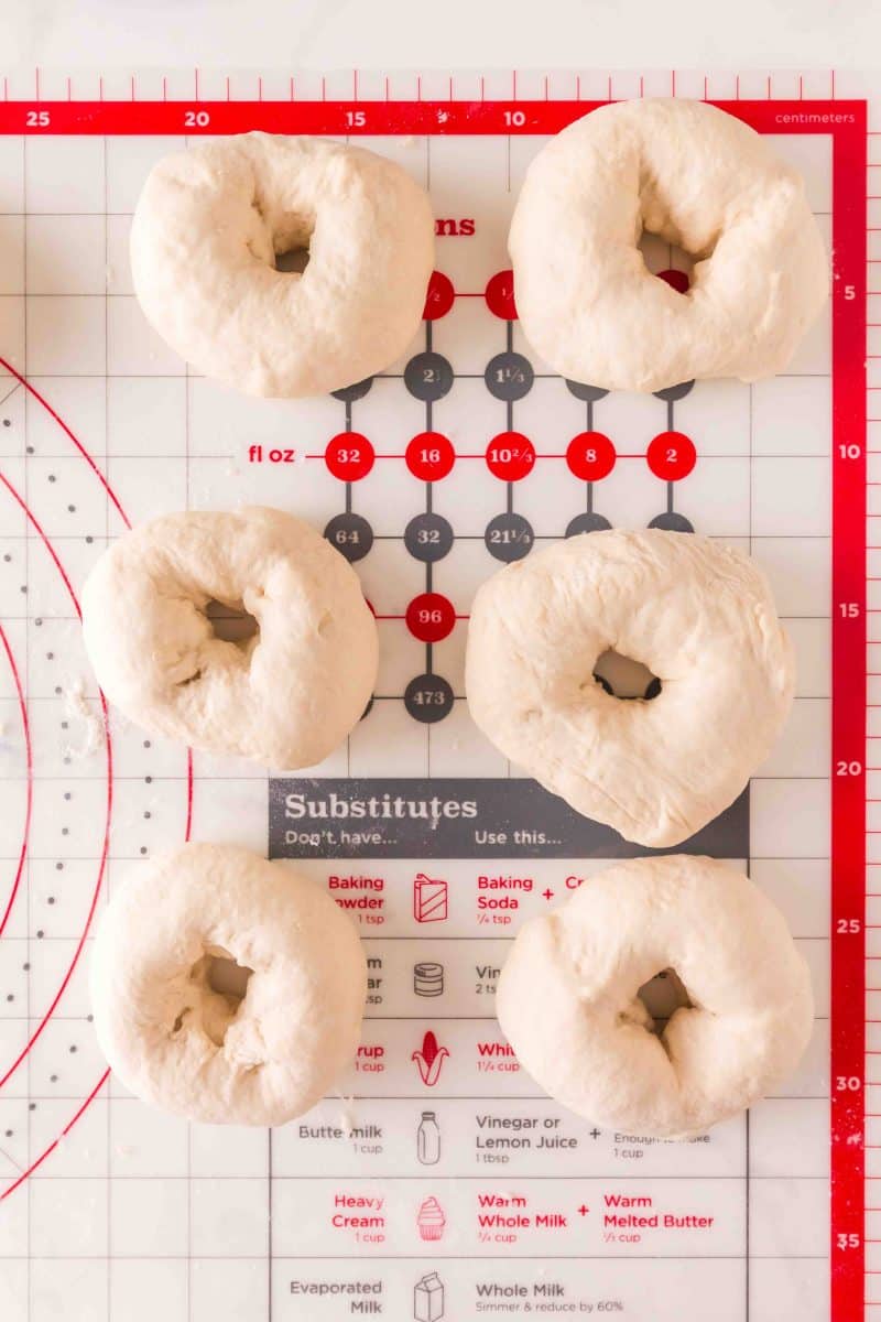 Yeast dough shaped into homemade bagels on a pastry mat. Hostess At Heart