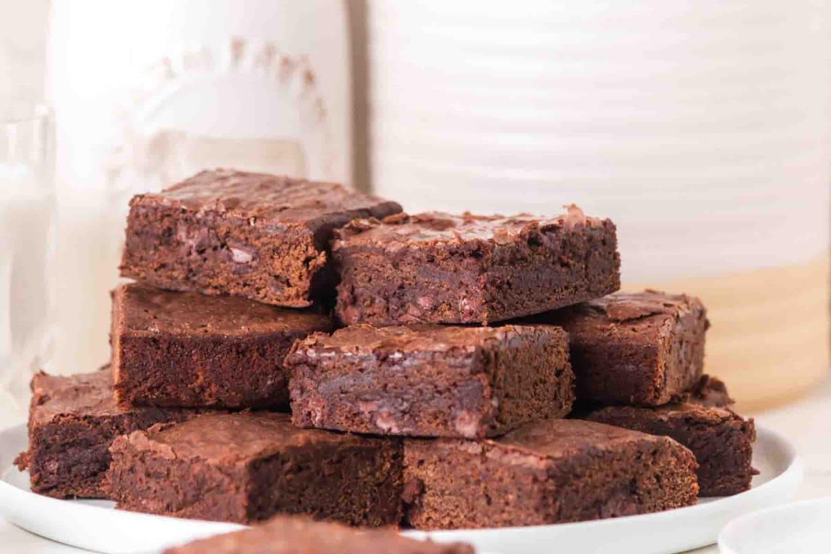 Stack of fudgy sourdough brownies with chocolate chips on white plate. Hostess At Heart