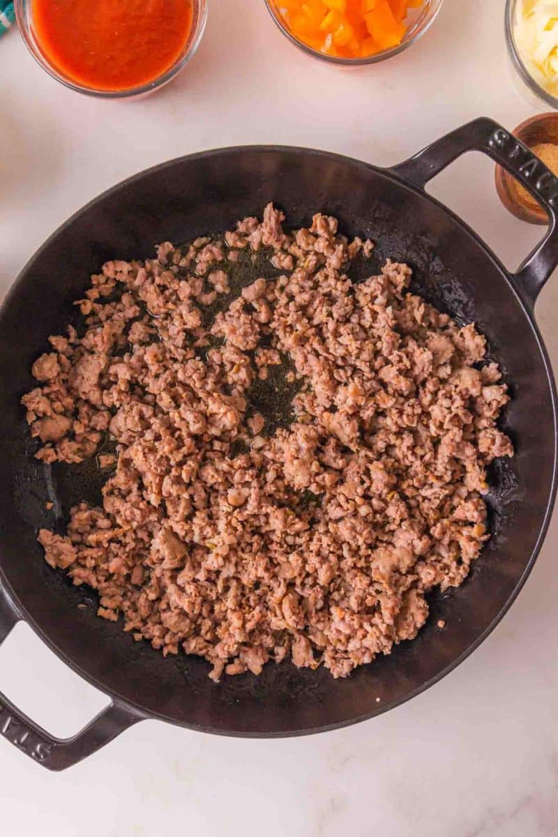 A cast iron filled with cooked ground Italian sausage. Hostess At Heart