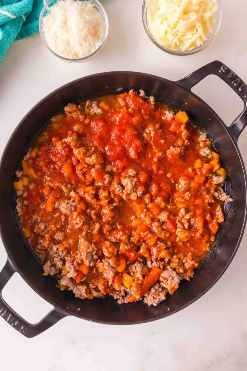 Combining cooked rigatoni pasta with Italian sausage marinara sauce. Hostess At Heart