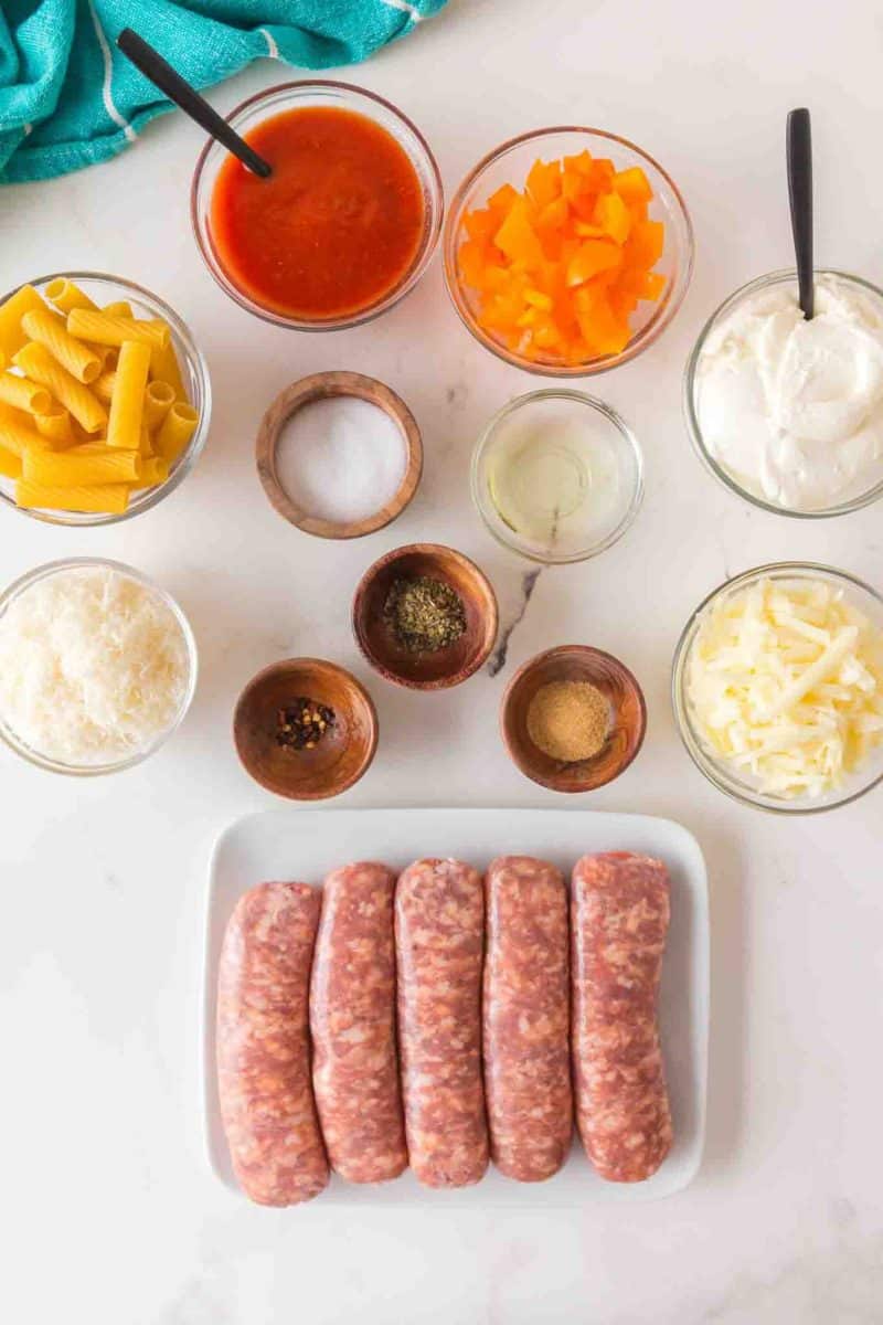 Ingredients for baked rigatoni recipe including rigatoni pasta, Italian sausage, ricotta cheese, and marinara sauce. Hostess At Heart
