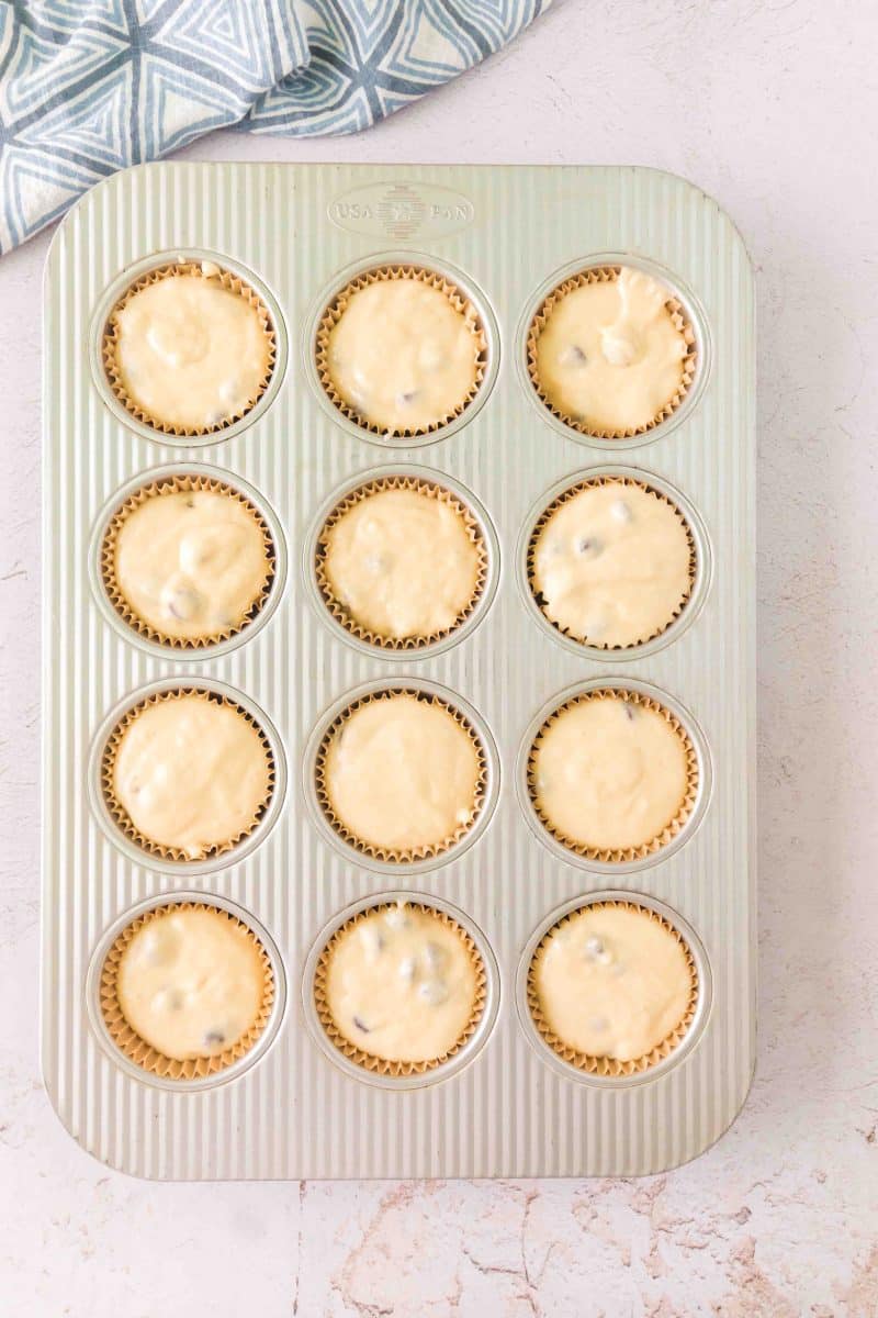 Top down view of a muffin pan with muffin liners properly filled sourdough chocolate chip batter. Hostess At Heart