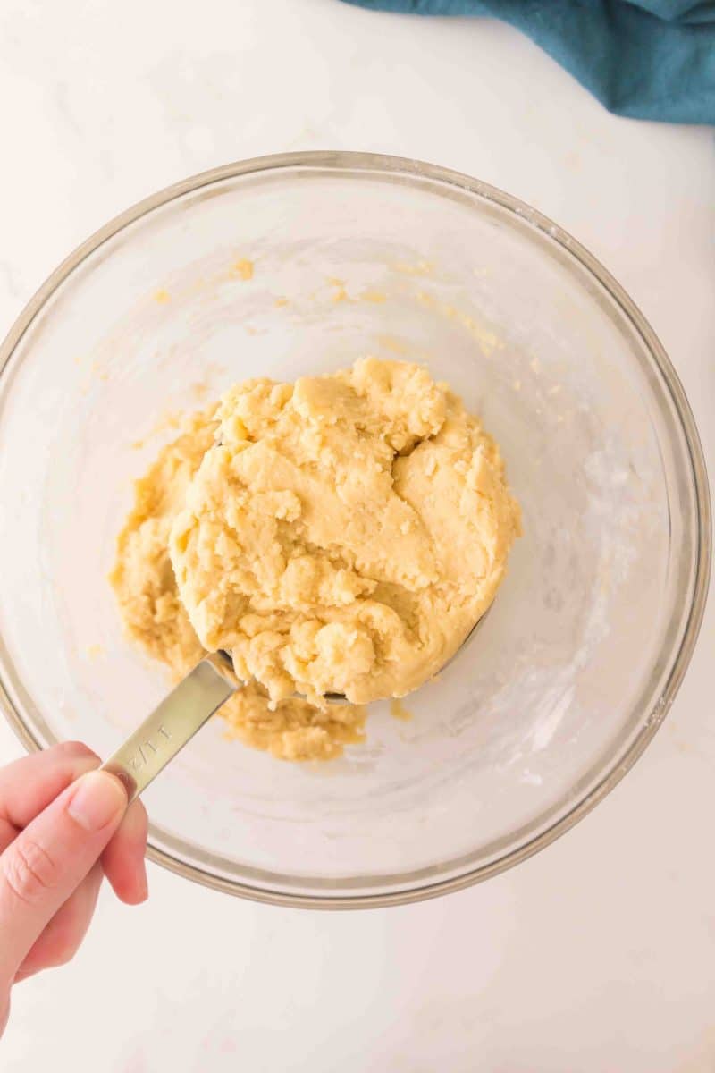 A measuring cup filled with reserved cherry crumble dough. Hostess At Heart