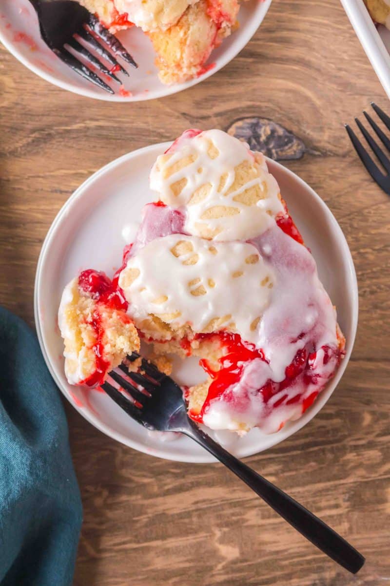 Single Cherry Pie Bar on a plate with a fork, showing the buttery layers. Hostess At Heart