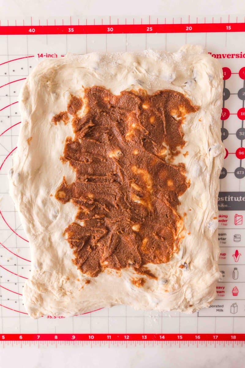 Brown cinnamon butter mixture spread onto stretched rectangle of bread dough on floured surface. Hostess At Heart