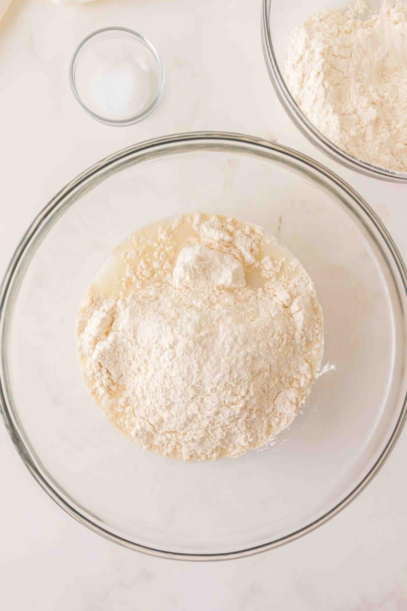 Flour added to a milky mixture of water and sourdough starter in a mixing bowl. Hostess At Heart