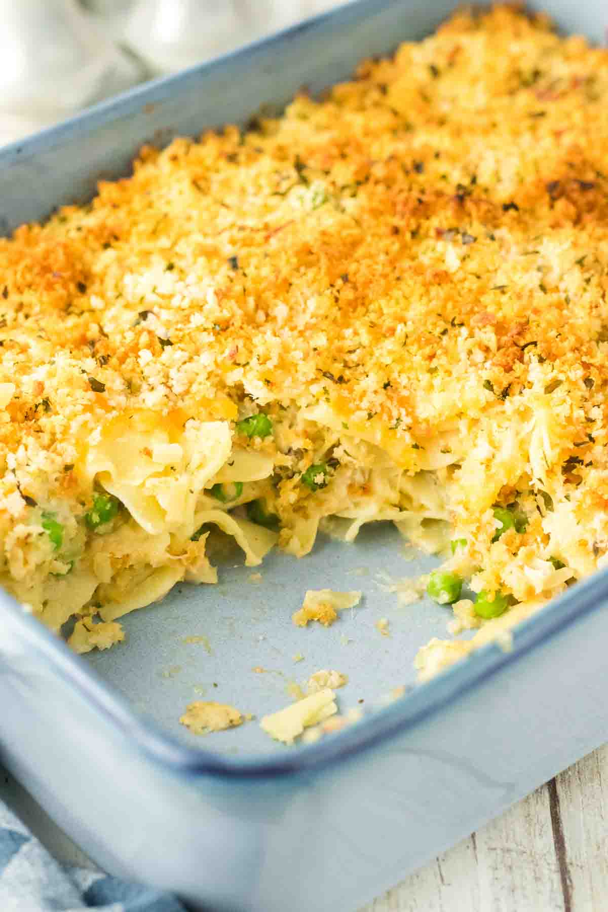 Angled view of a baking dish with a serving of tuna noodle casserole missing showing the creamy ingredients - Hostess At Heart