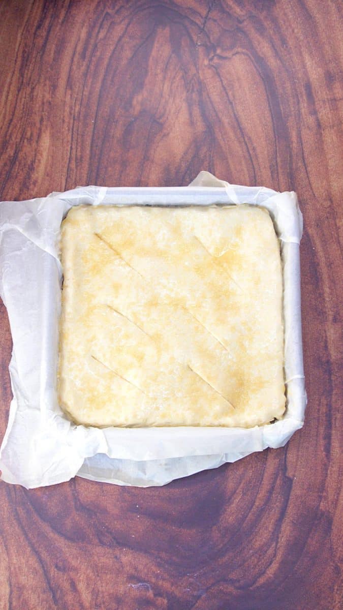 Top down view of a pie covered with pie crust that's been washed with an egg wash and sprinkled with turbinado sugar. Hostess At Heart