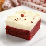 Red velvet brownie on plate showing soft moist interior and a thick cream cheese frosting layer. Hostess At Heart