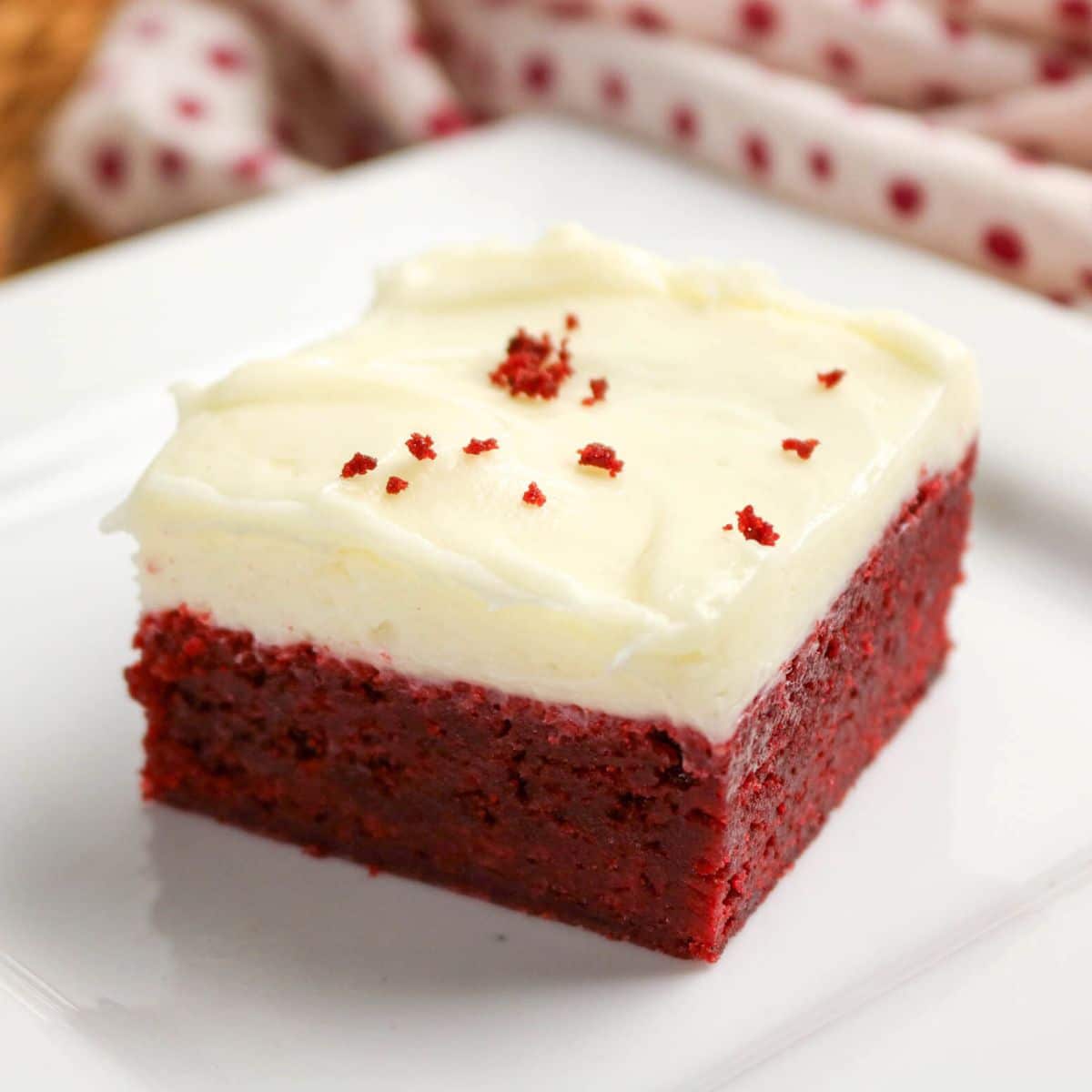 Red velvet brownie on plate showing soft moist interior and a thick cream cheese frosting layer. Hostess At Heart