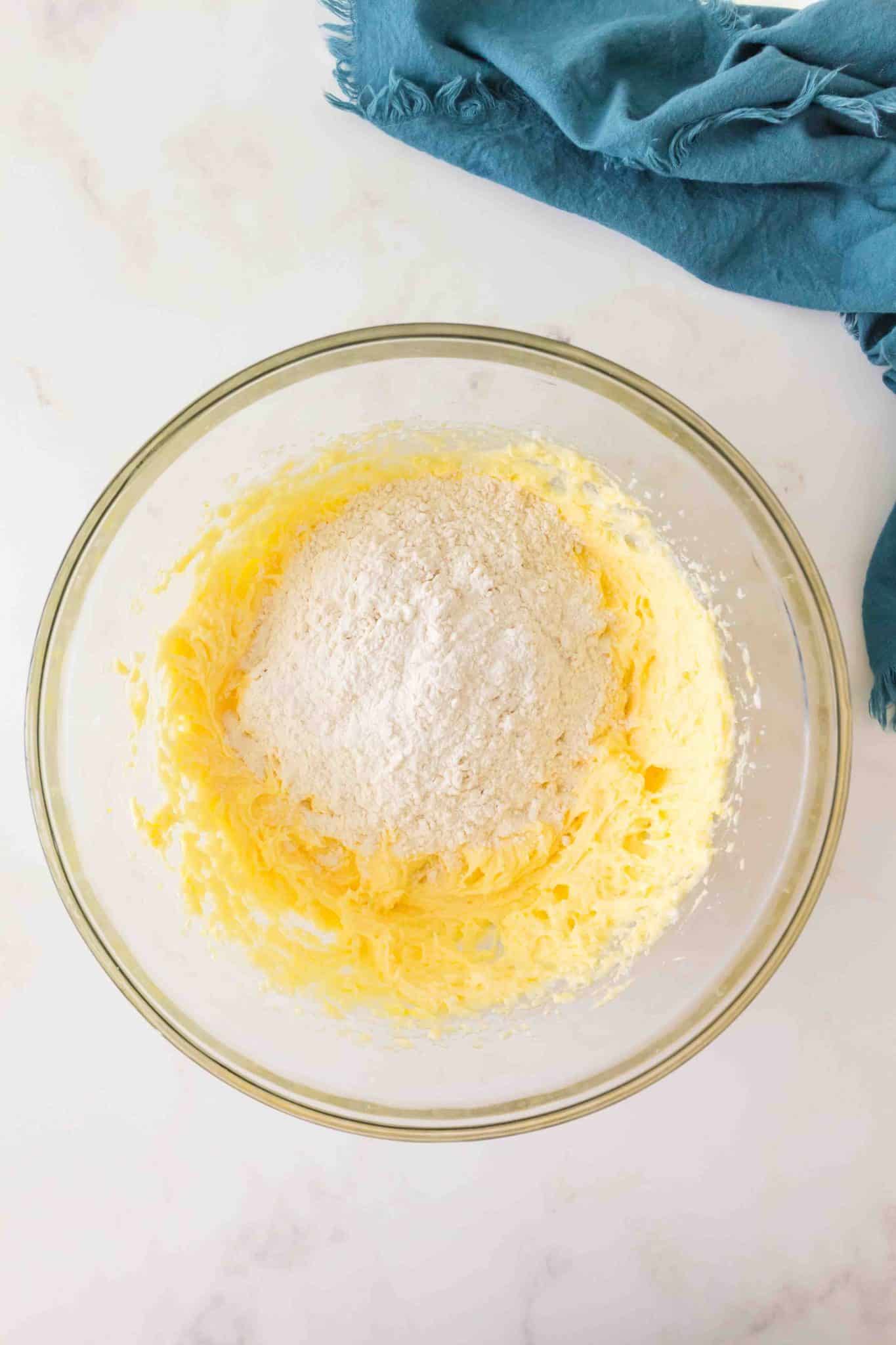 A mixing bowl showing flour added to a creamy mixture of butter and shortening to make cherry pie crumble crust. Hostess At Heart