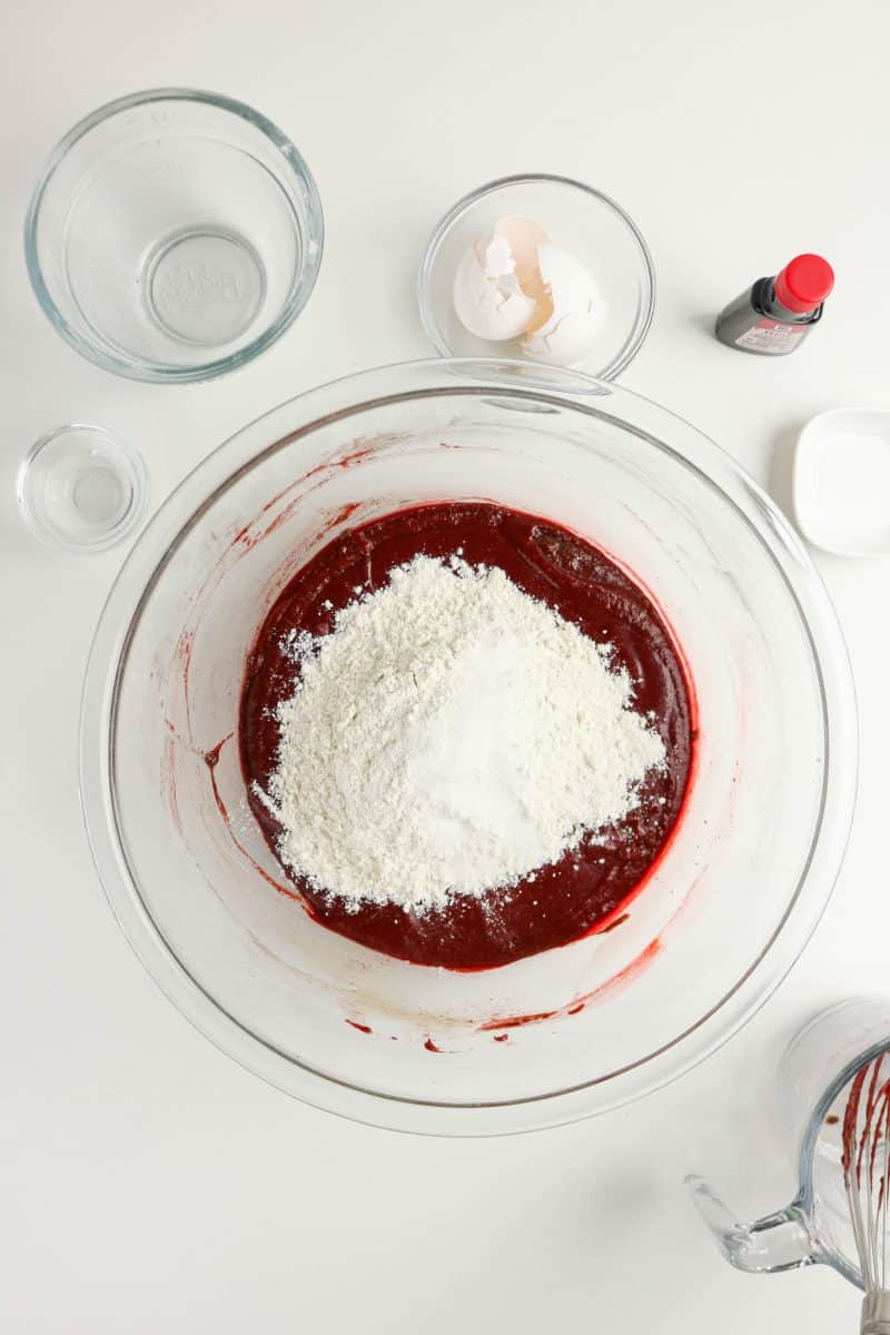 Flour and salt added to creamed red velvet batter in a mixing bowl to make red velvet cake brownies. Hostess At Heart